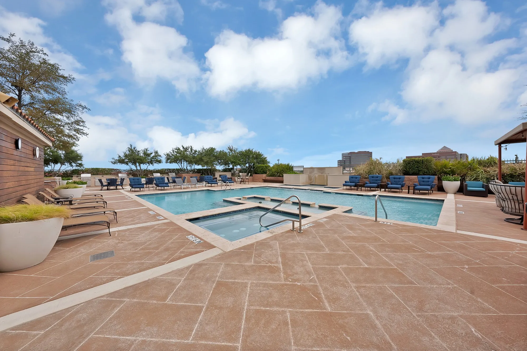 Expansive outdoor pool area featuring a rectangular pool, integrated spa, and spacious paver deck