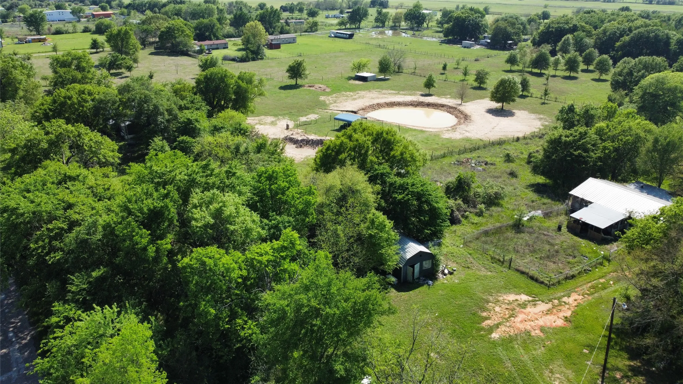 Expansive rural property featuring an established pond, a barn structure, and mature trees
