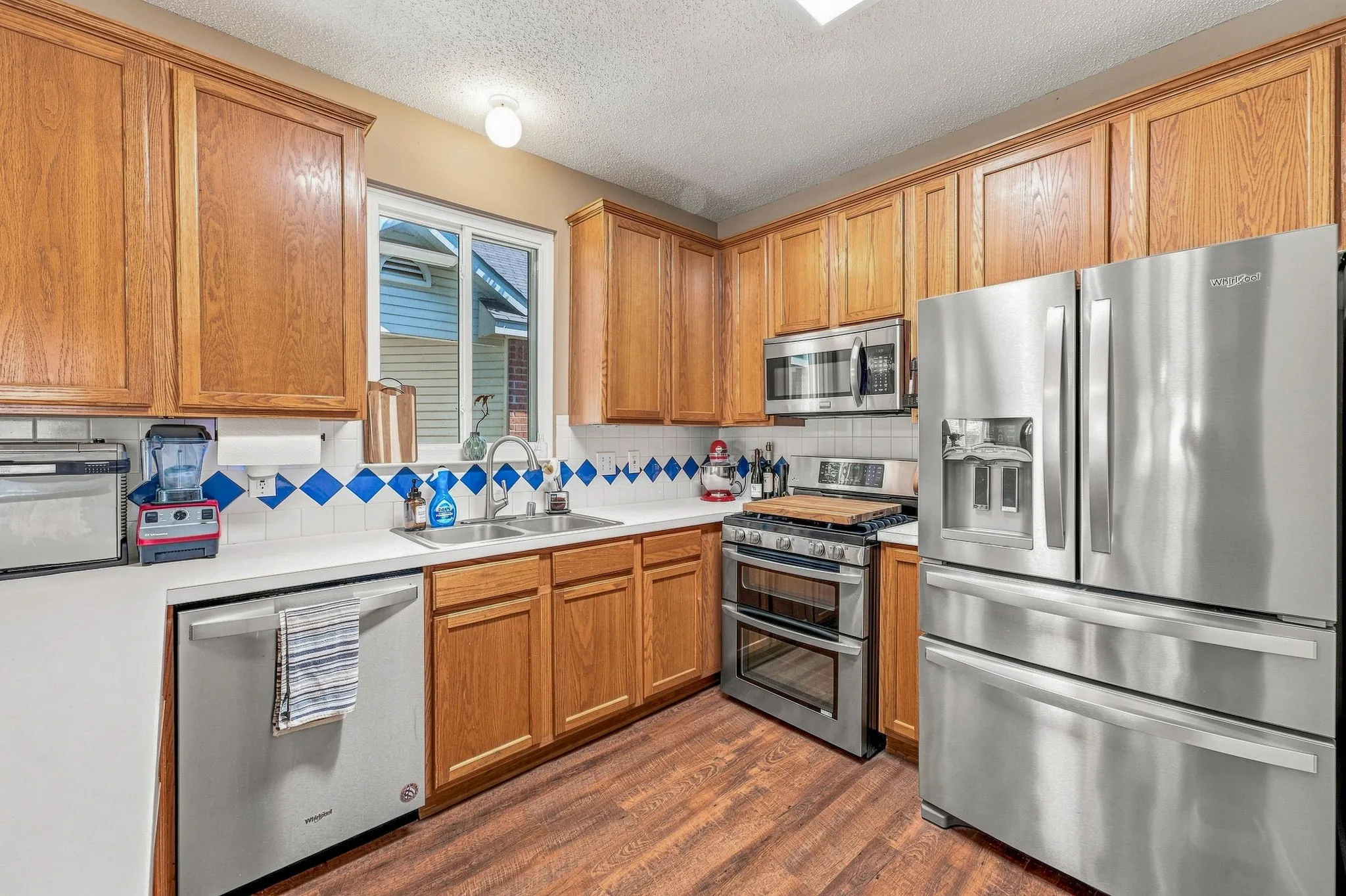 Kitchen featuring wood cabinetry, stainless steel appliances, white countertops, and wood-finish flooring