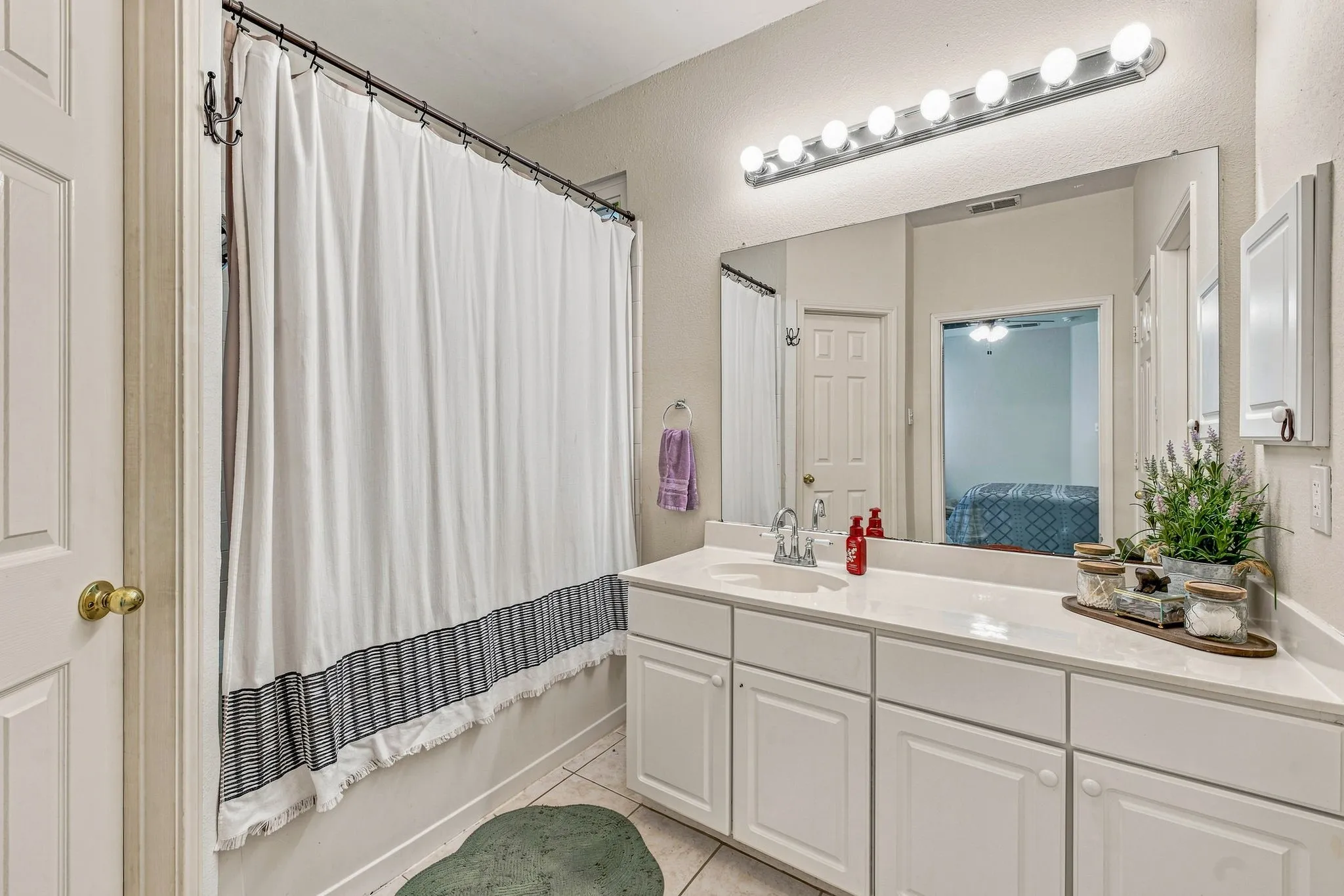 Vanity with an integrated sink, white cabinetry, and a large wall-mounted mirror