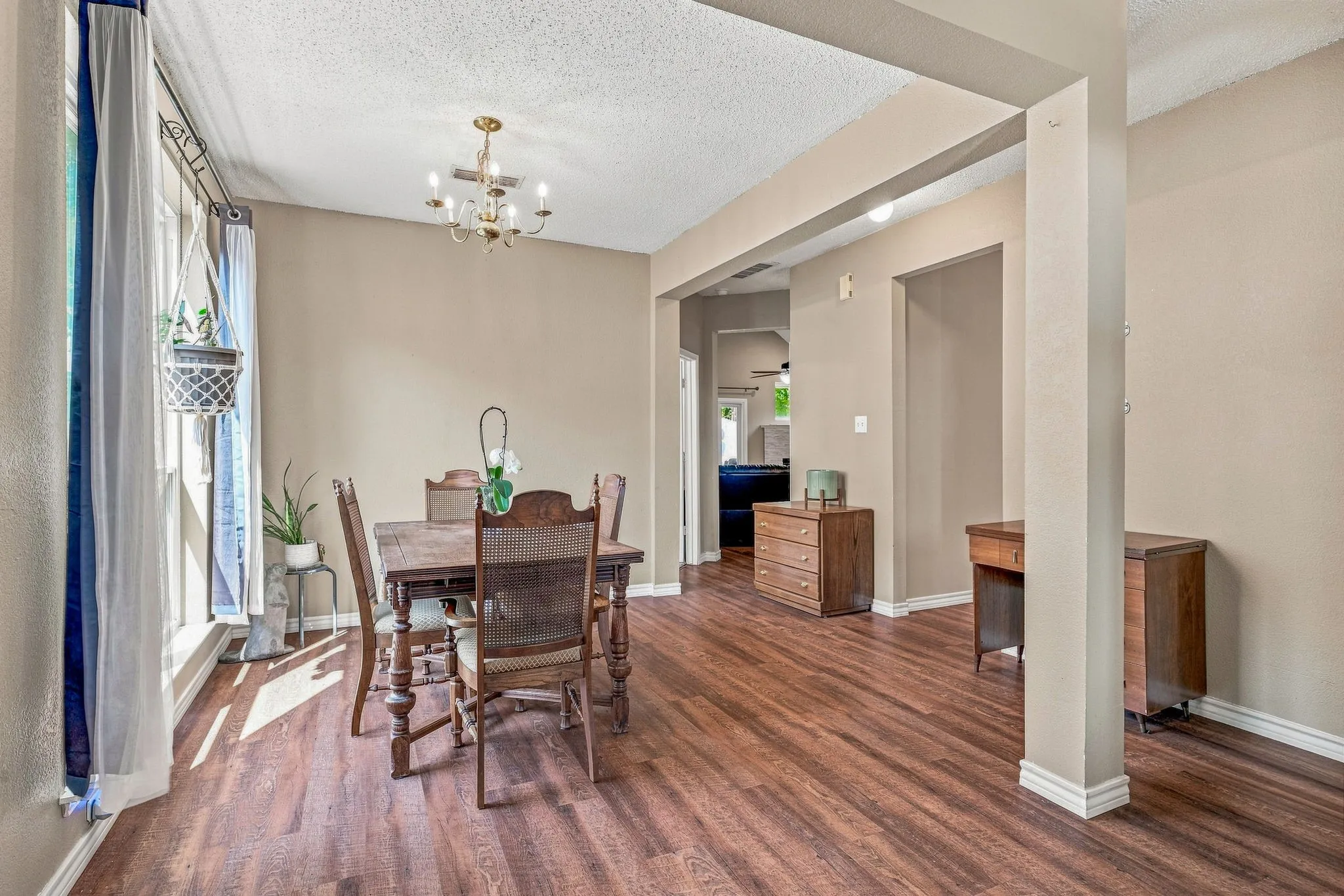 Wood-finish flooring throughout, featuring a classic chandelier, open doorways, and neutral wall tones