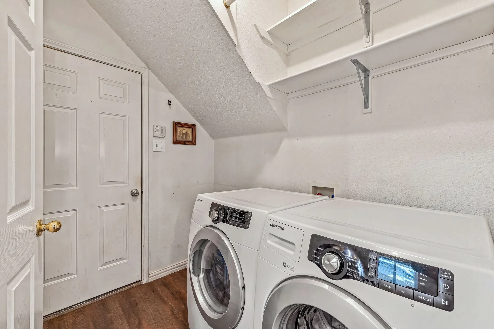 Laundry area with wood-finish flooring and built-in shelving