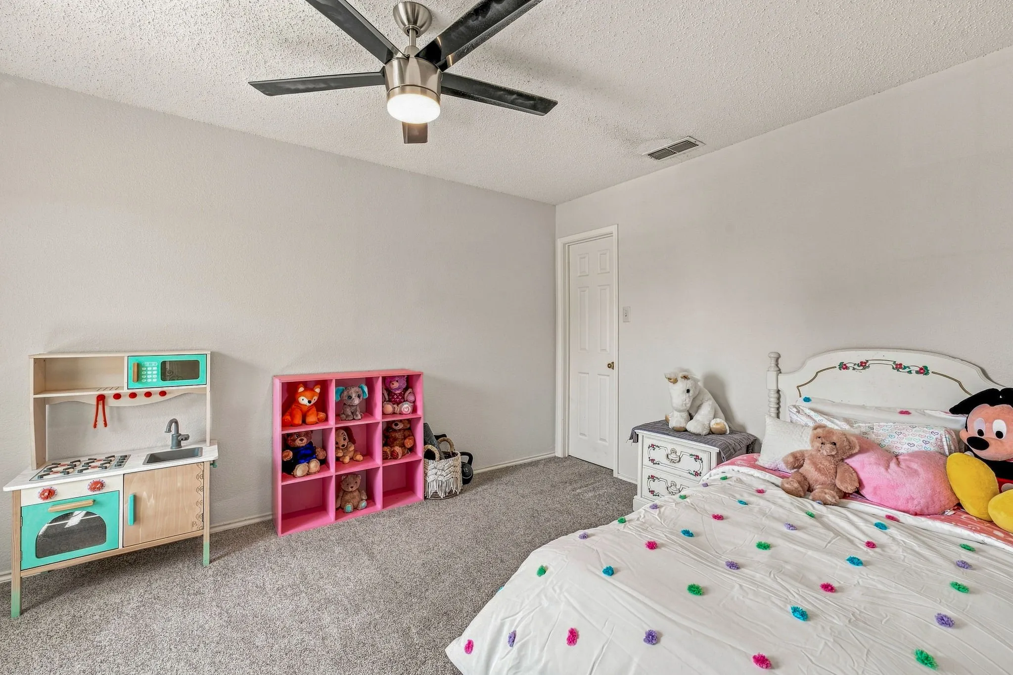 Carpeted flooring, ceiling fan with integrated lighting, white interior door with a round knob, textured ceiling, and light-colored wall paint