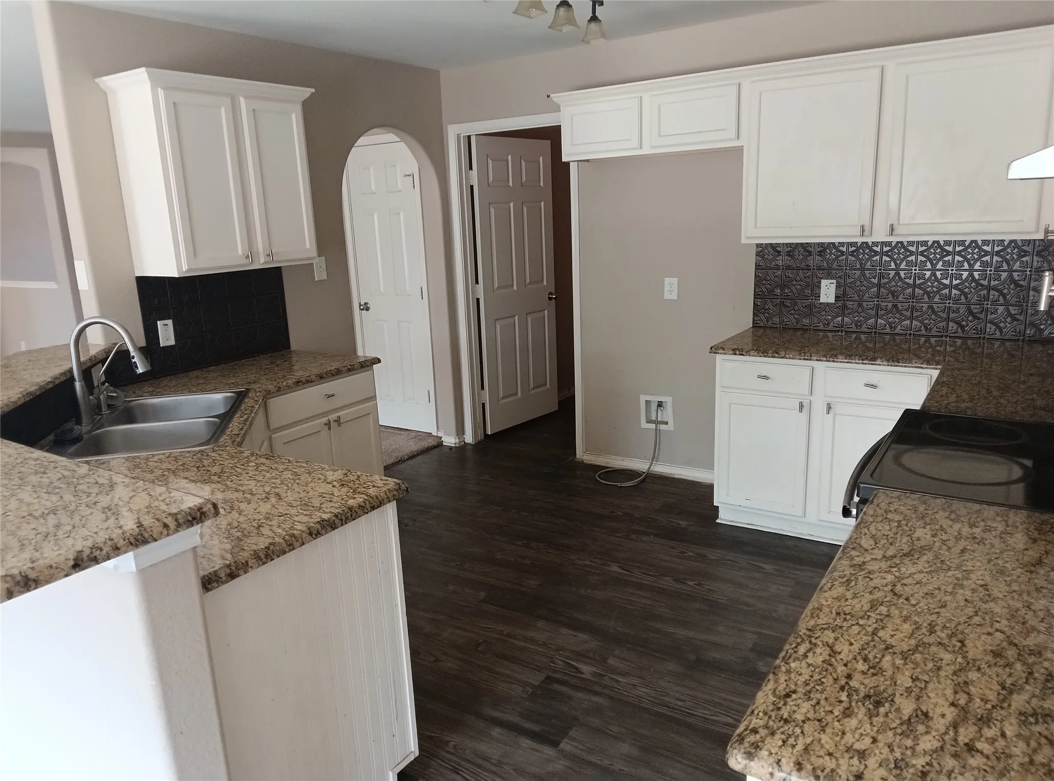 Kitchen featuring wood-finish flooring, white cabinetry, speckled countertops, and a patterned backsplash