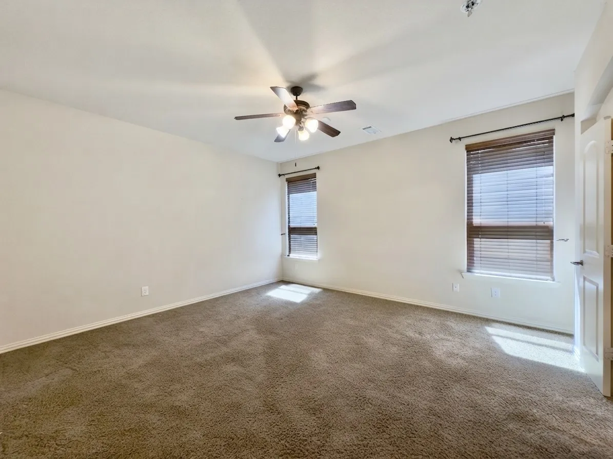 Recessed lighting, ceiling fan with integrated lighting, two windows with blinds, and neutral tone carpeting