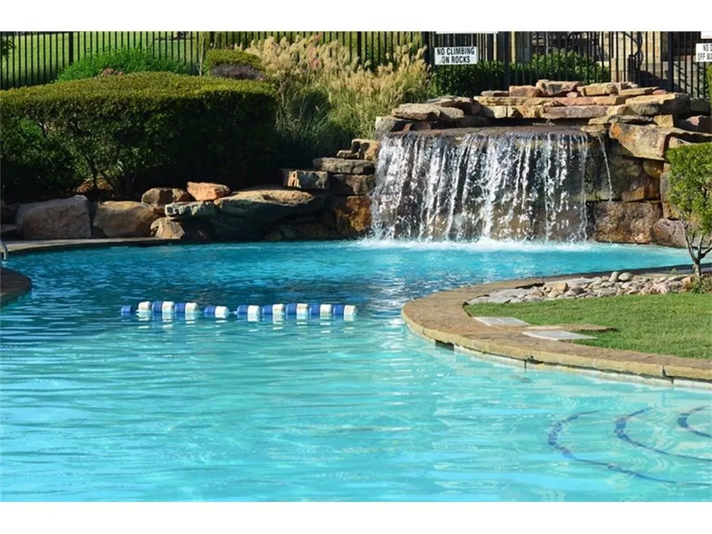 Aquatic area featuring a rock waterfall, stepped entry, and perimeter landscaping