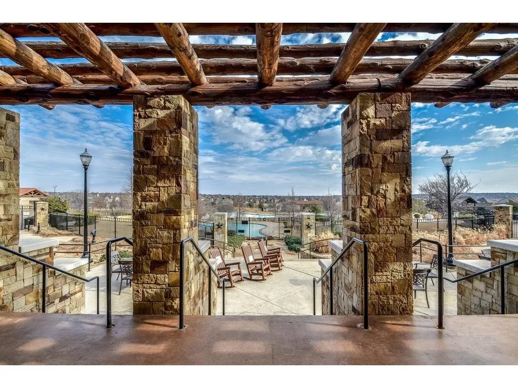 Wood beam pergola with stone columns and wrought iron railings