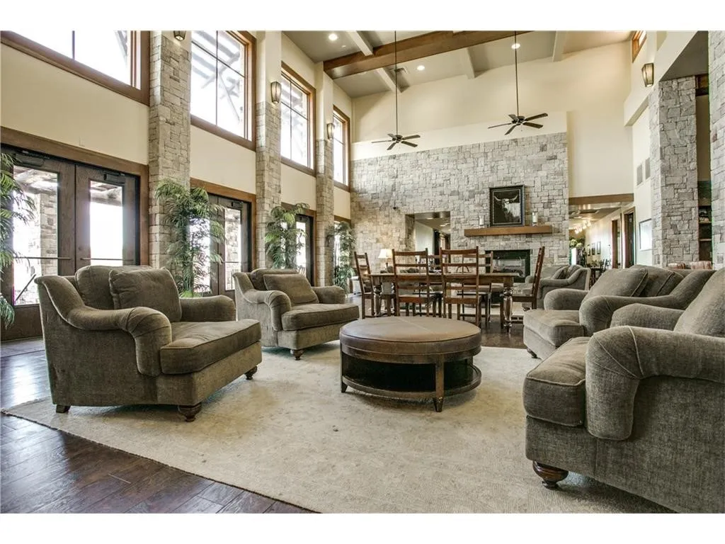 Expansive room with high vaulted ceilings, stone accent walls, wood-finish flooring, and multiple ceiling fans