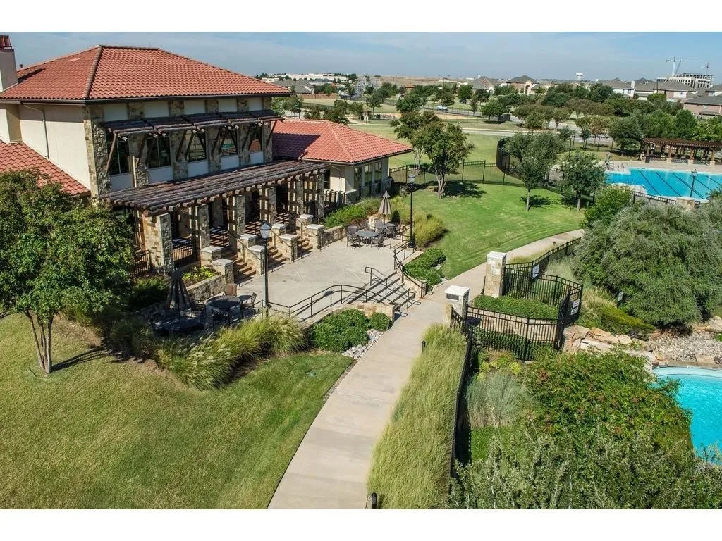 Terracotta tile roof, stone and stucco exterior, expansive patio, mature landscaping, and swimming pool
