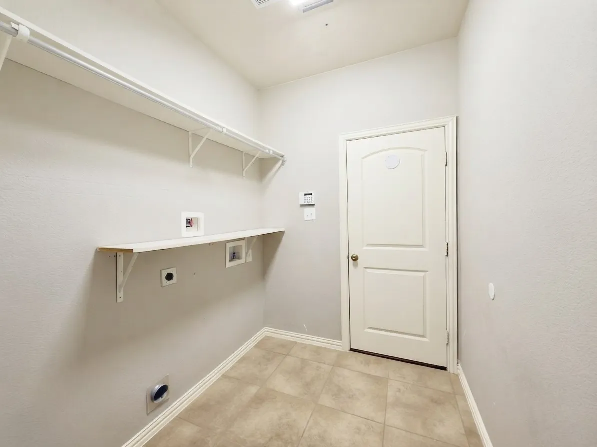 Utility room with tile flooring, wall-mounted shelving, and a built-in countertop