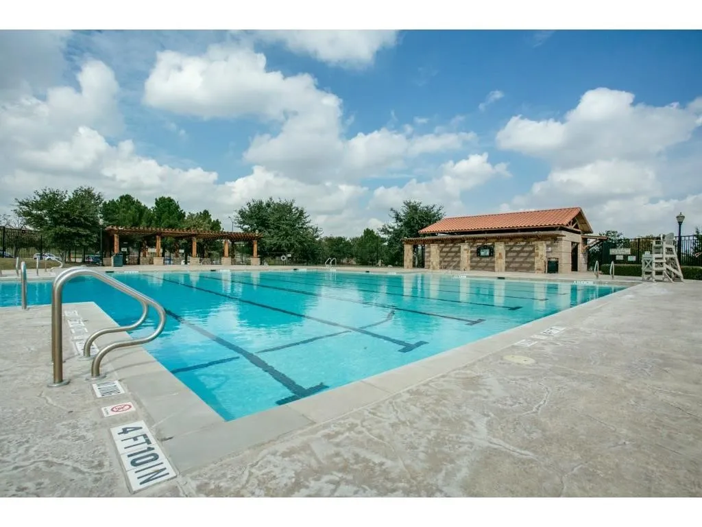 Expansive outdoor swimming pool with lane lines, concrete decking, and stainless steel handrails