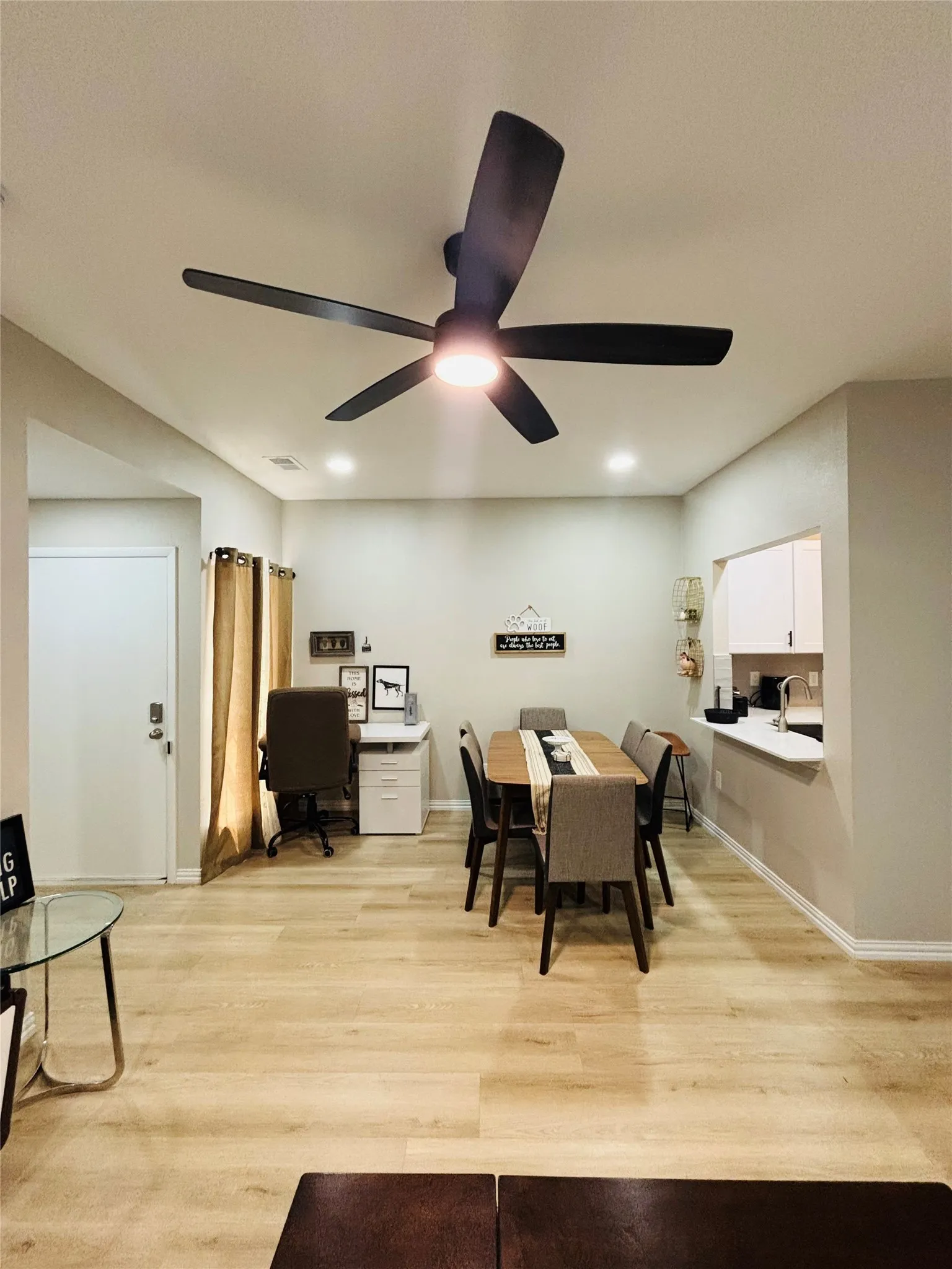 Recessed ceiling lighting, wood-finish flooring, ceiling fan, white trim, and a pass-through window with a countertop