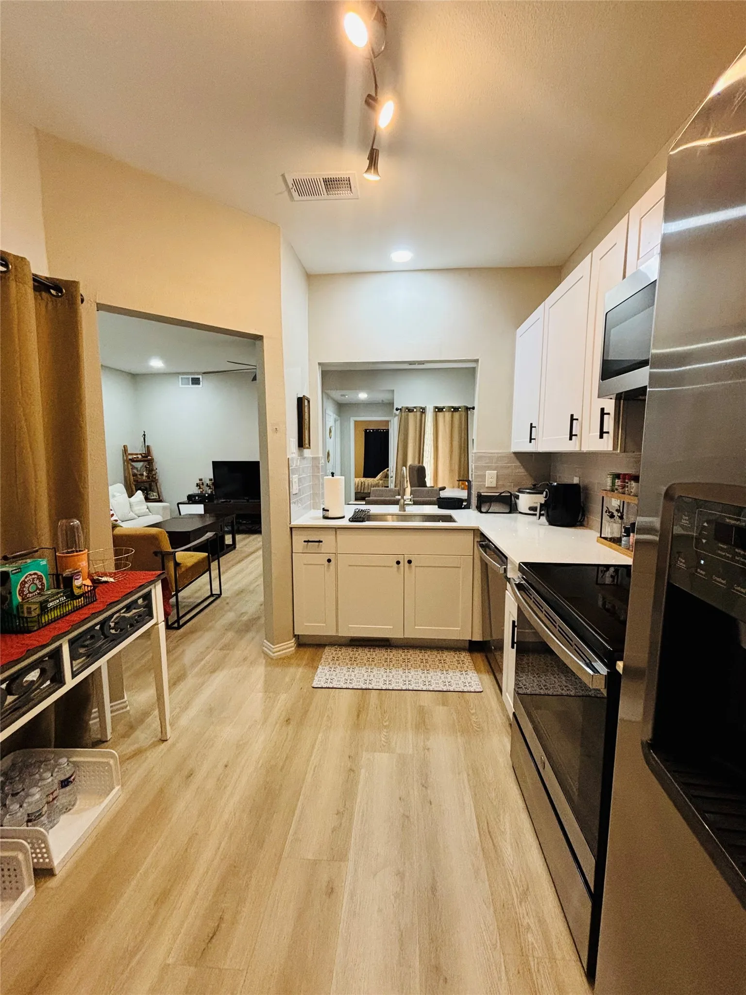 Kitchen featuring wood-finish flooring, white cabinetry, a white countertop, and stainless steel appliances