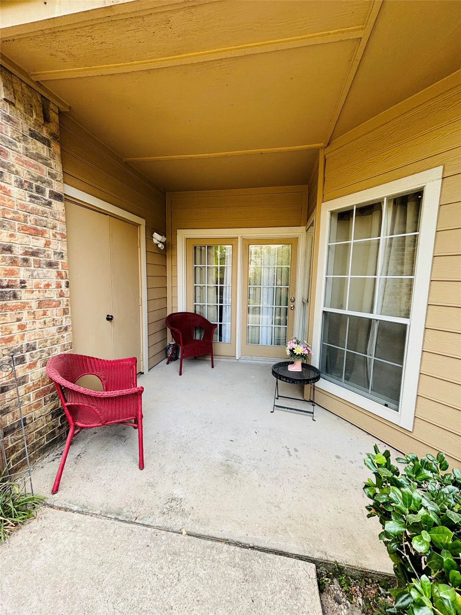 Covered concrete patio with a storage closet and a double-pane window