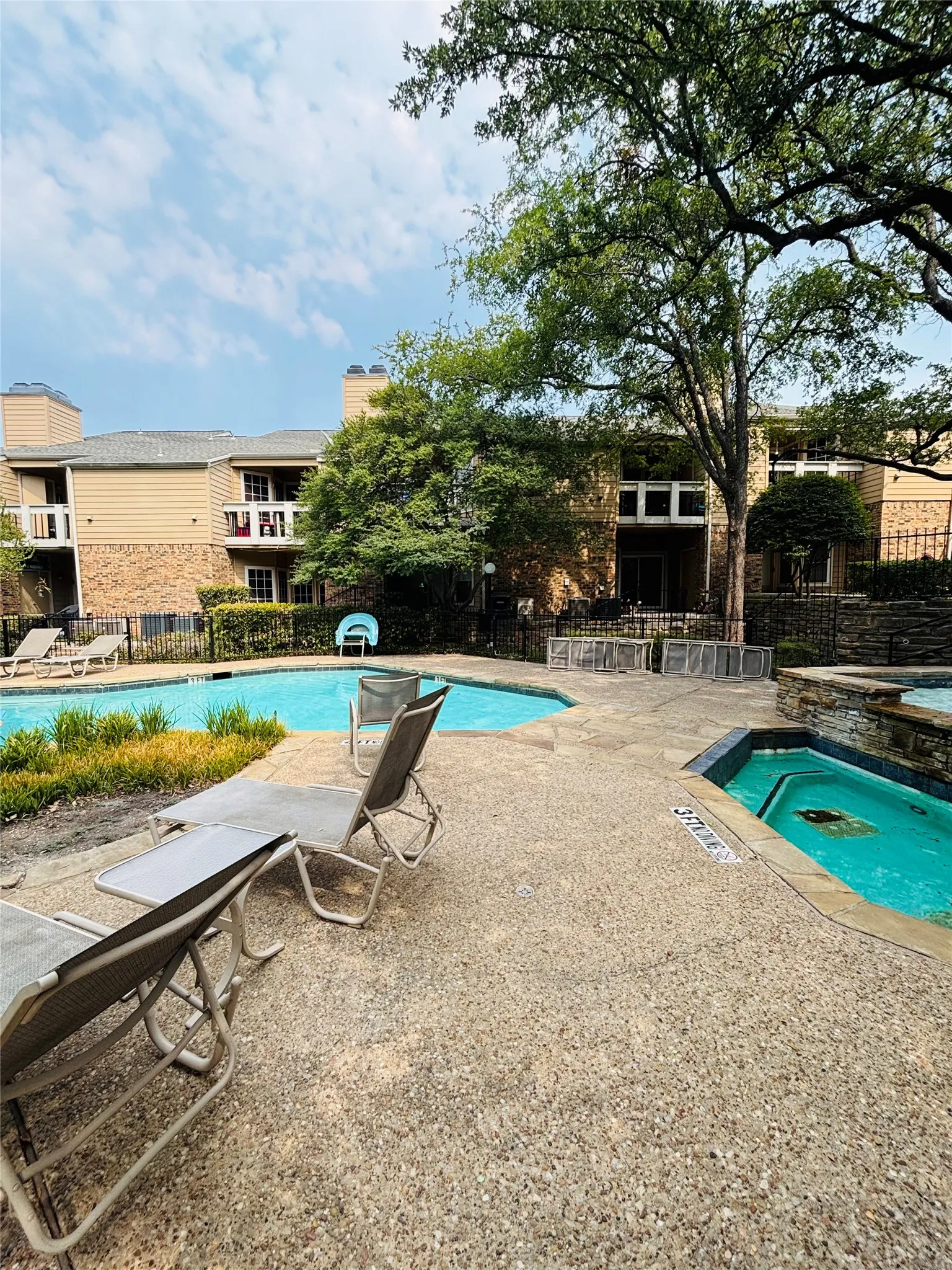 Expansive outdoor area featuring a swimming pool, integrated spa, and exposed aggregate concrete decking