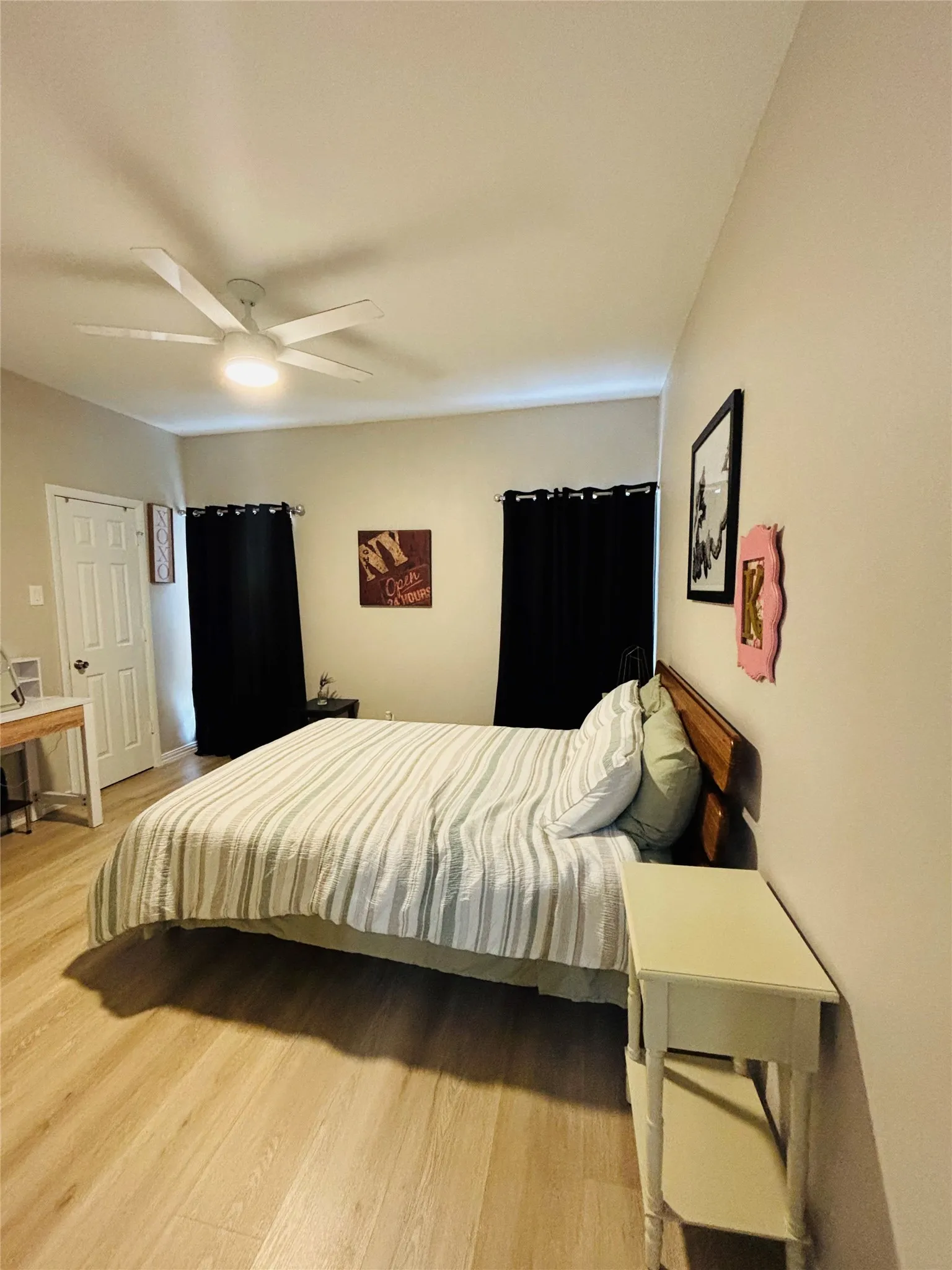 Wood-finish flooring, white ceiling fan with integrated lighting, and neutral wall tones