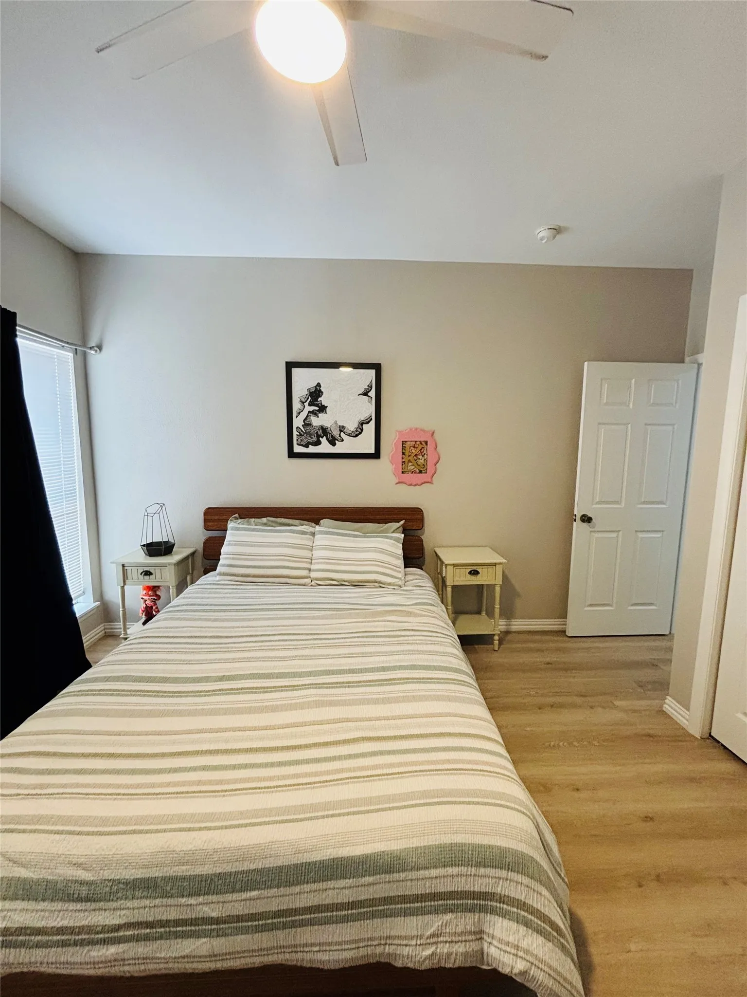 Wood-finish flooring, ceiling fan with integrated lighting, window with blinds, and paneled door