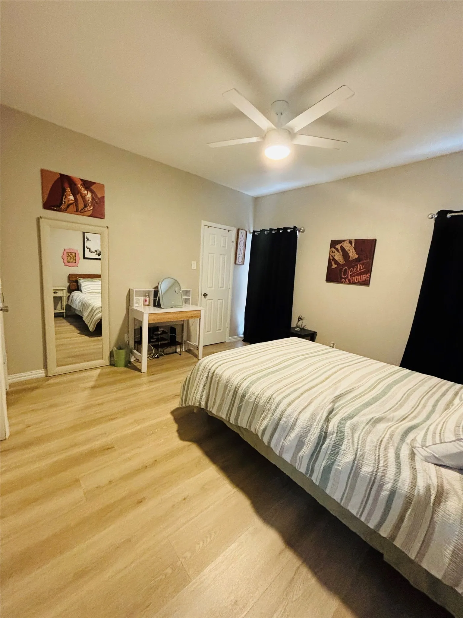 Wood-finish flooring throughout, complemented by a contemporary ceiling fan with integrated lighting, and neutral wall tones