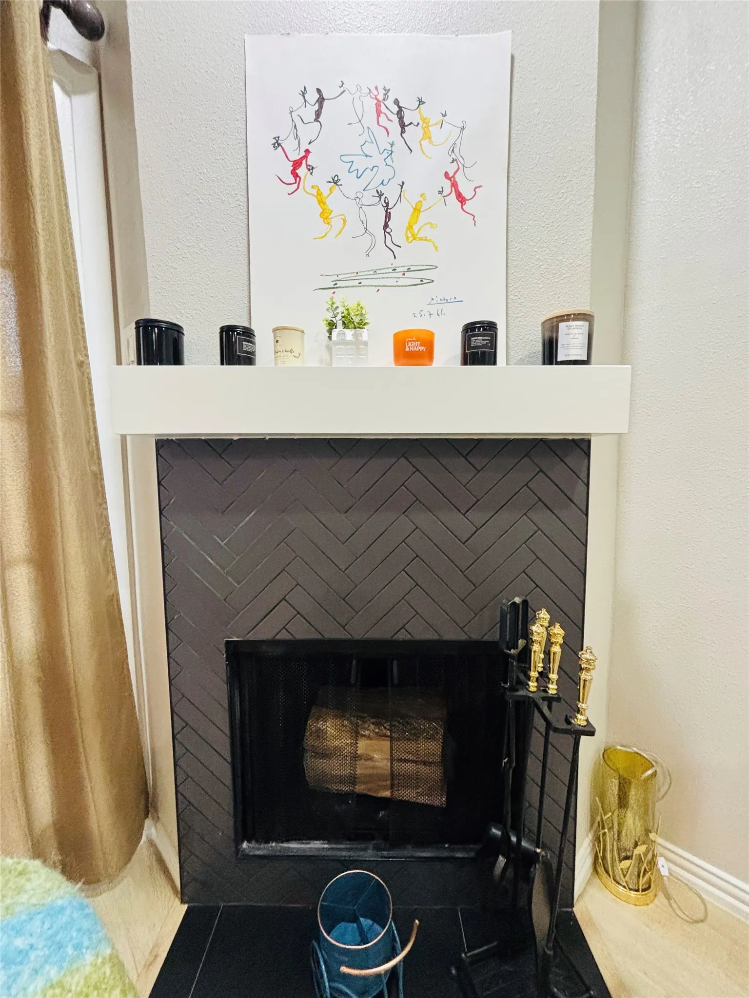 Fireplace featuring dark herringbone tile surround, a crisp white mantel, and a black firebox