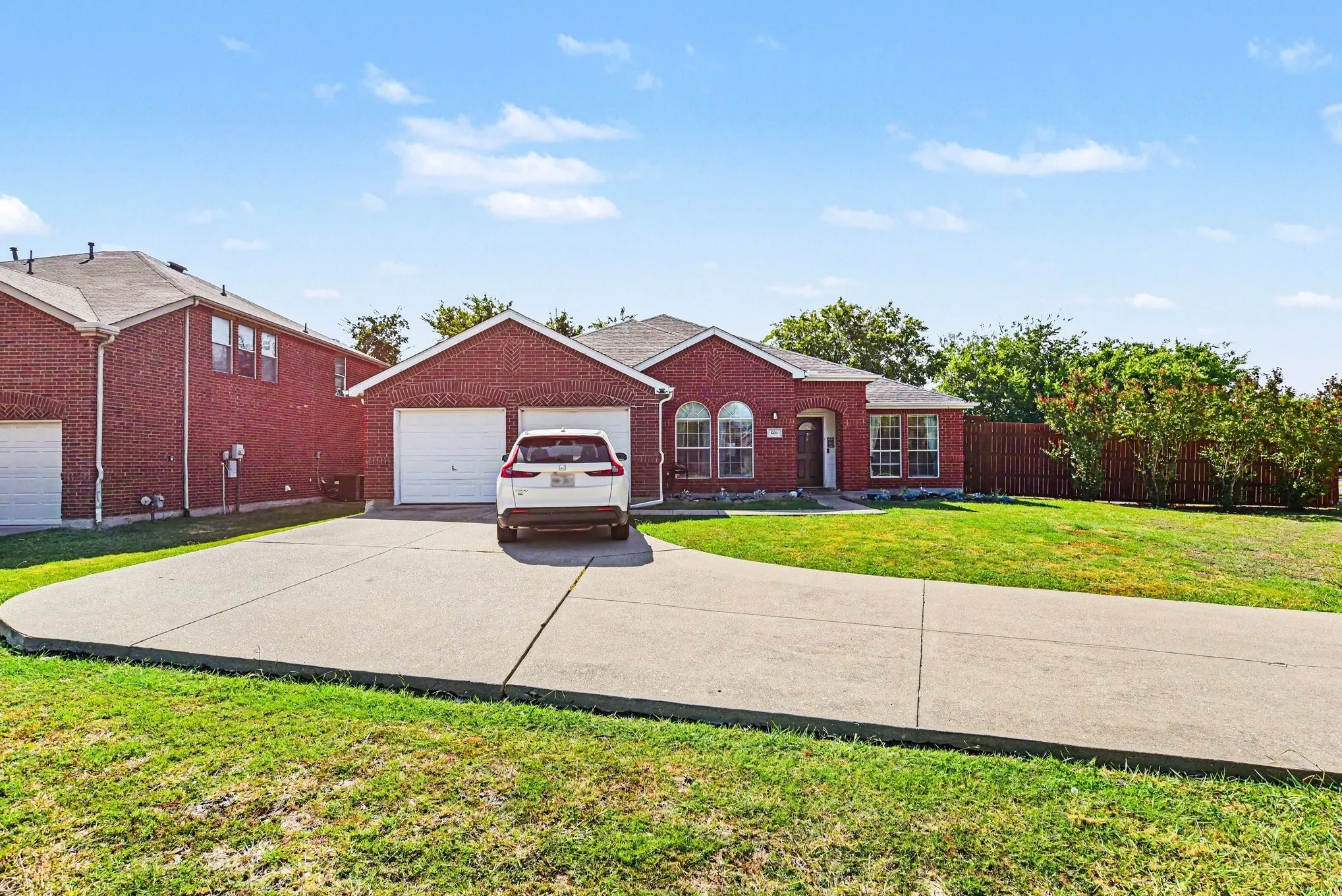 Brick exterior with arched window details, an attached two-car garage, and a concrete driveway