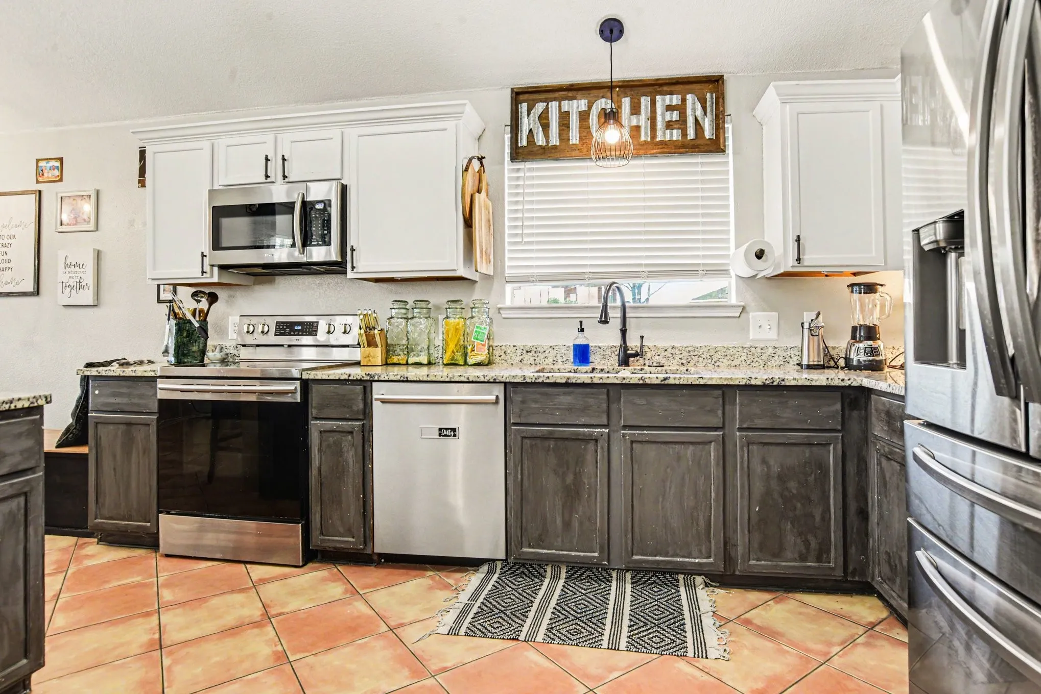 Kitchen featuring two-tone cabinetry, stainless steel appliances, granite-style countertops, and a single basin sink with a gooseneck faucet