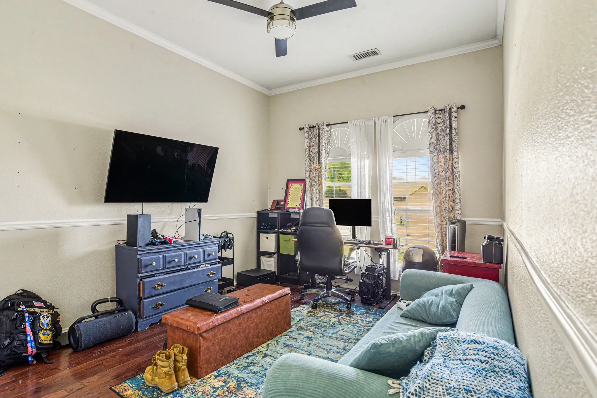 Wood-finish flooring, crown molding, and a ceiling fan create a functional space