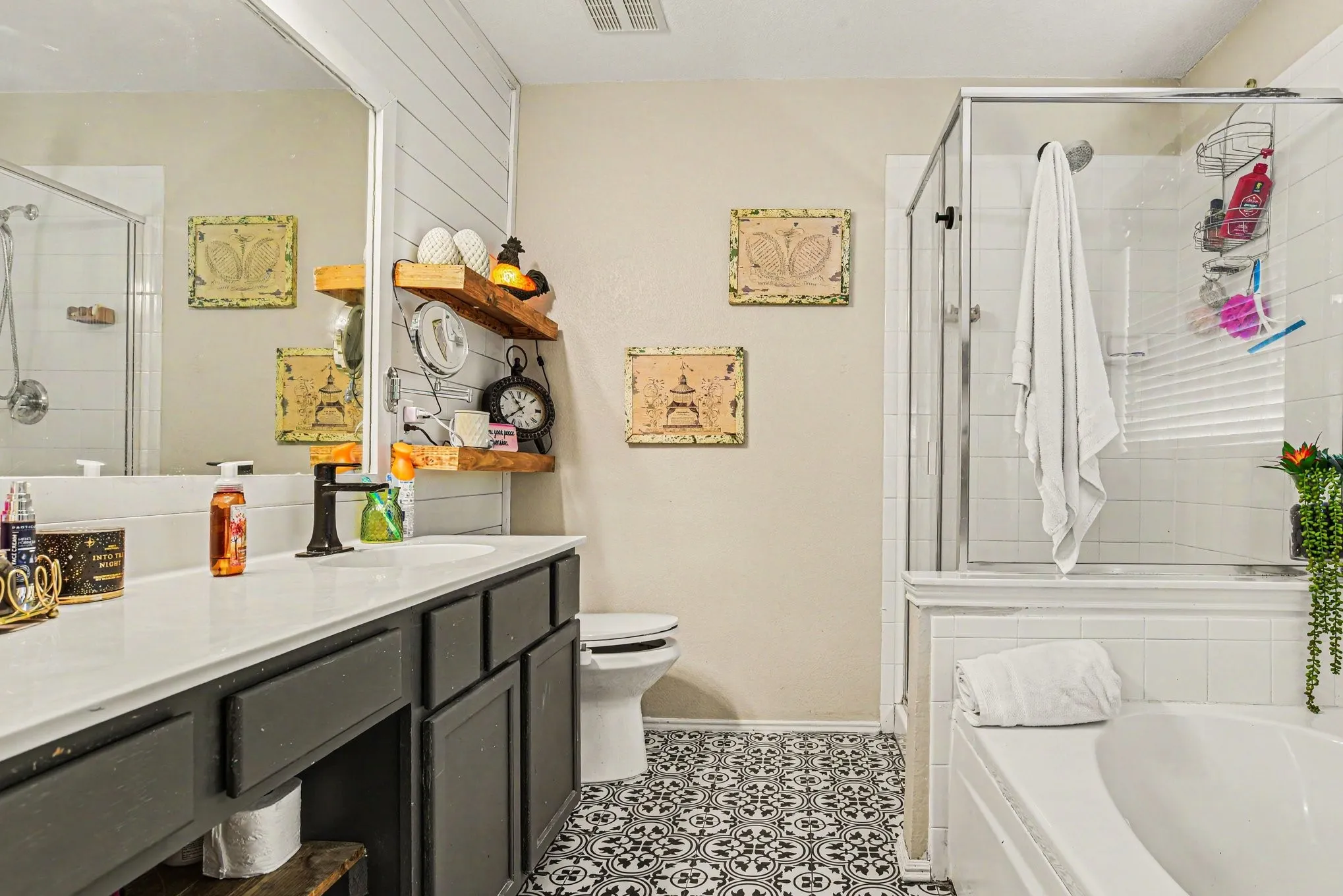 Bathroom featuring a single vanity with dark cabinetry, white countertop, and a built-in tub with shower
