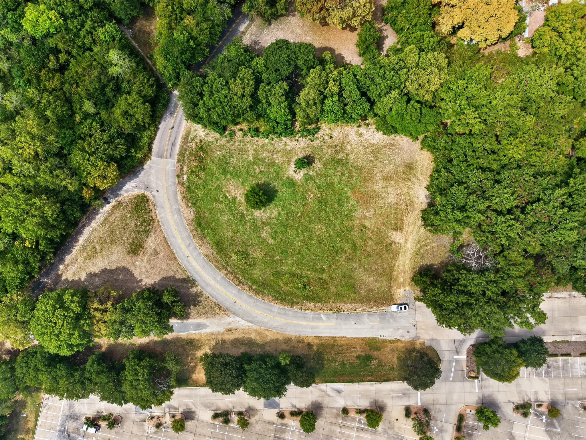 Expansive green space bordered by mature trees and paved roadways