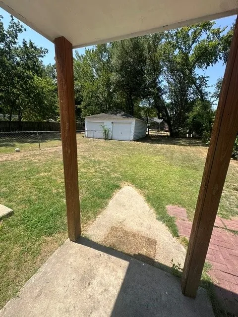 Expansive backyard featuring a detached two-car garage, mature trees, and a concrete patio