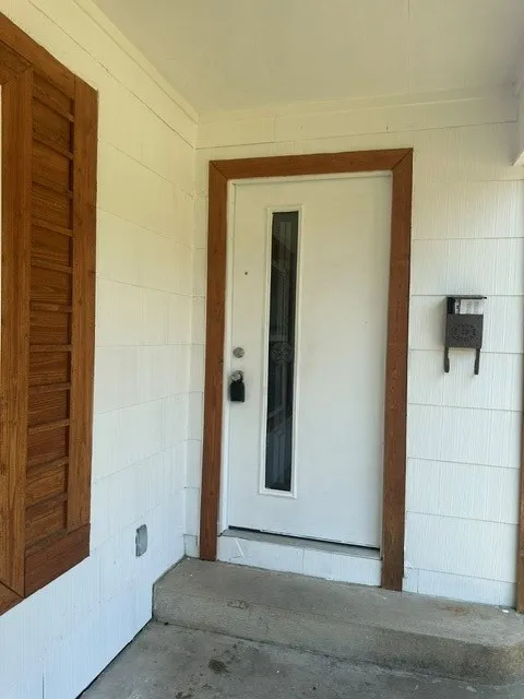White exterior siding with a complementary wood-finish door frame