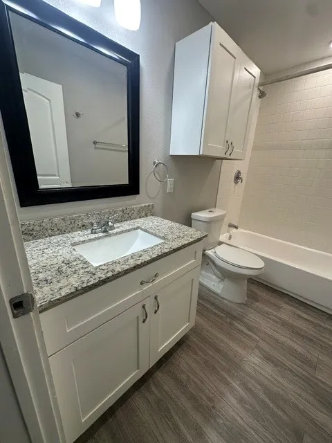 Vanity with integrated sink, speckled countertop, and white cabinetry