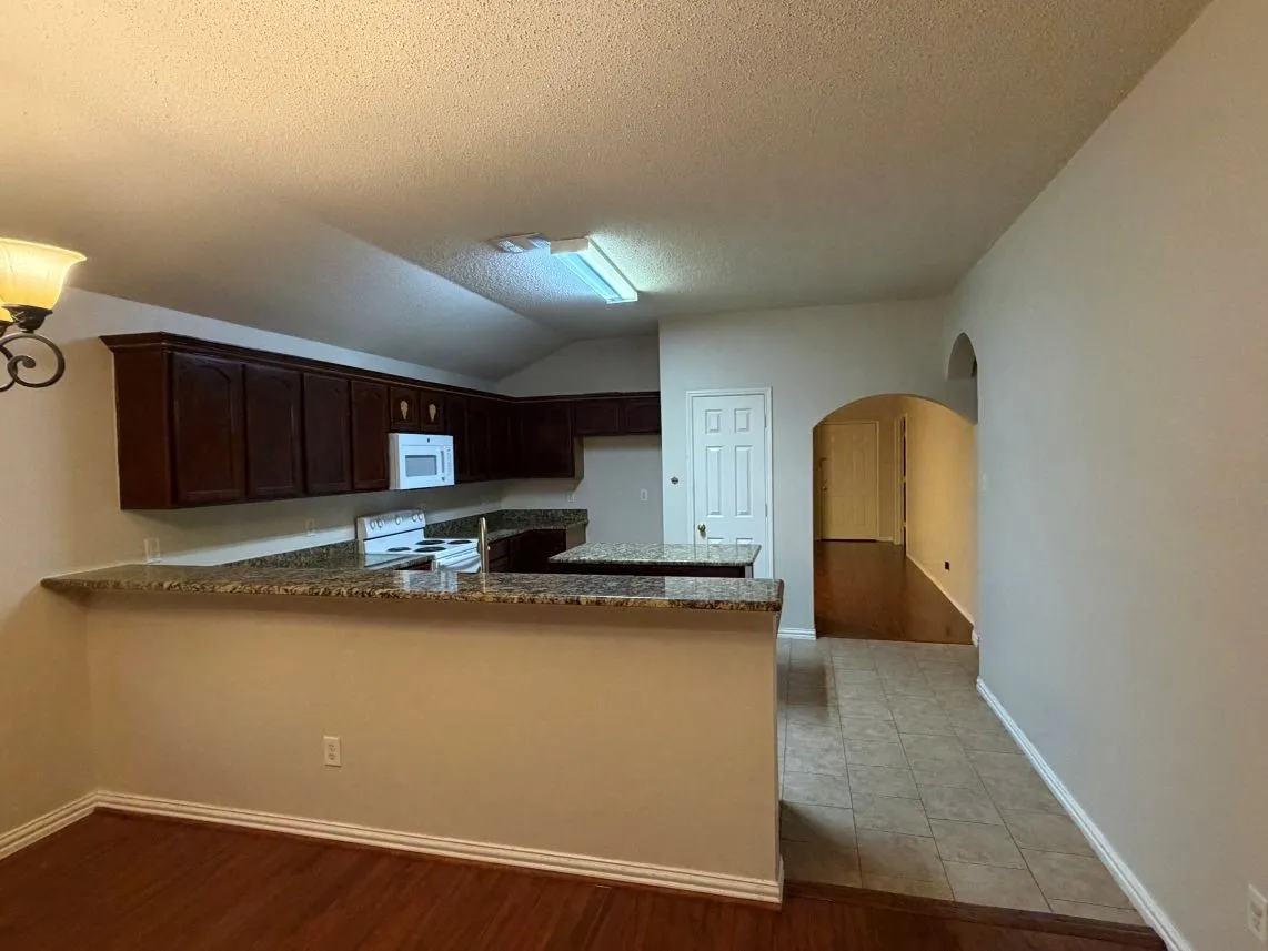 Kitchen featuring wood-finish cabinetry, light-toned countertops, and an integrated microwave
