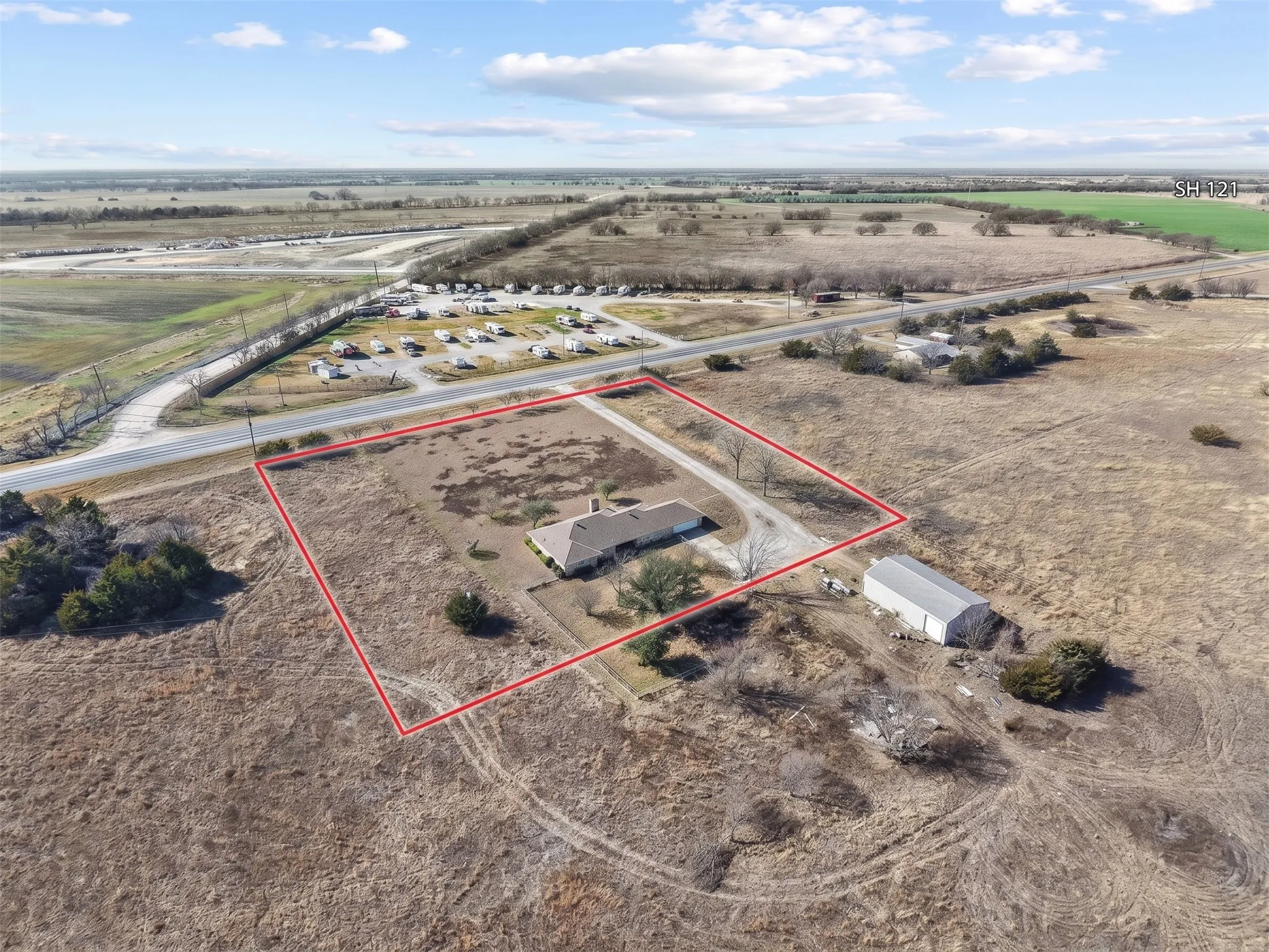 Expansive property featuring a single-story residence, gravel driveway, and a large outbuilding