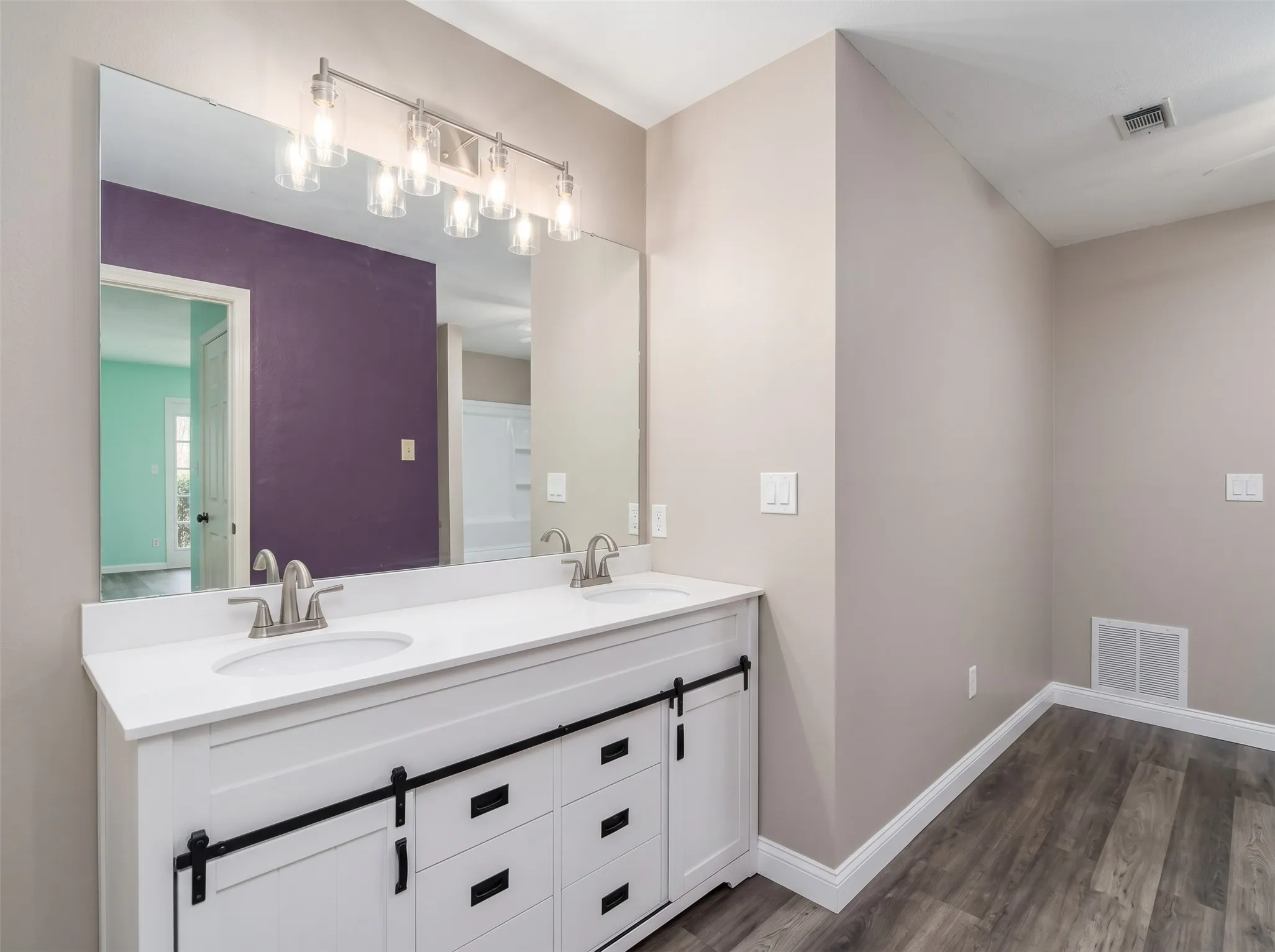 Dual vanity with white cabinetry, barn door style hardware, and a white countertop