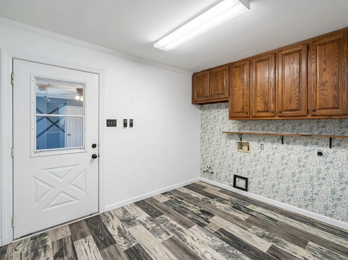 Wood-finish flooring, white paneled door with glass insert, built-in wooden cabinetry, and wall-mounted shelving