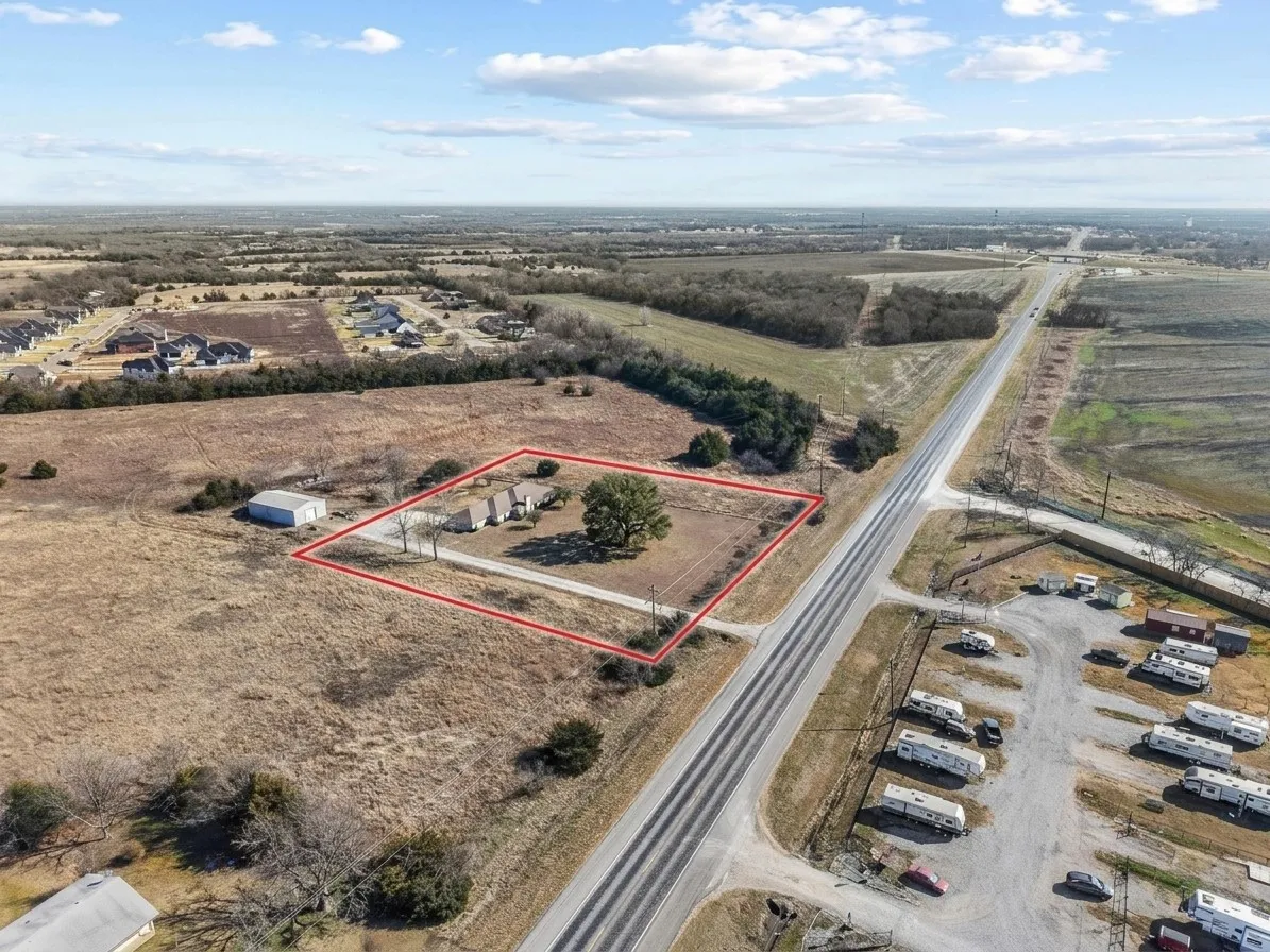 Expansive lot featuring a single-story residence with a light-toned exterior, a detached outbuilding, and mature trees