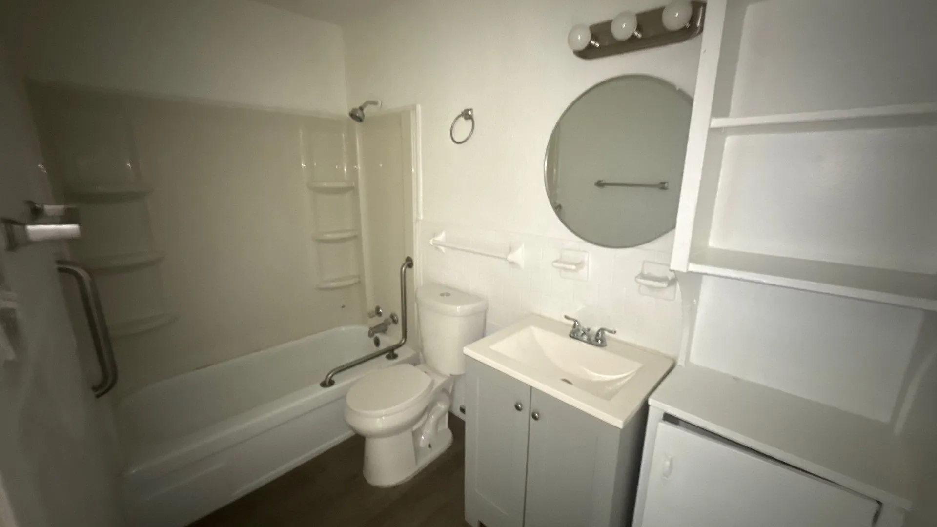 Bathroom featuring a shower/tub combination, circular vanity mirror, three-light vanity fixture, and a built-in storage unit