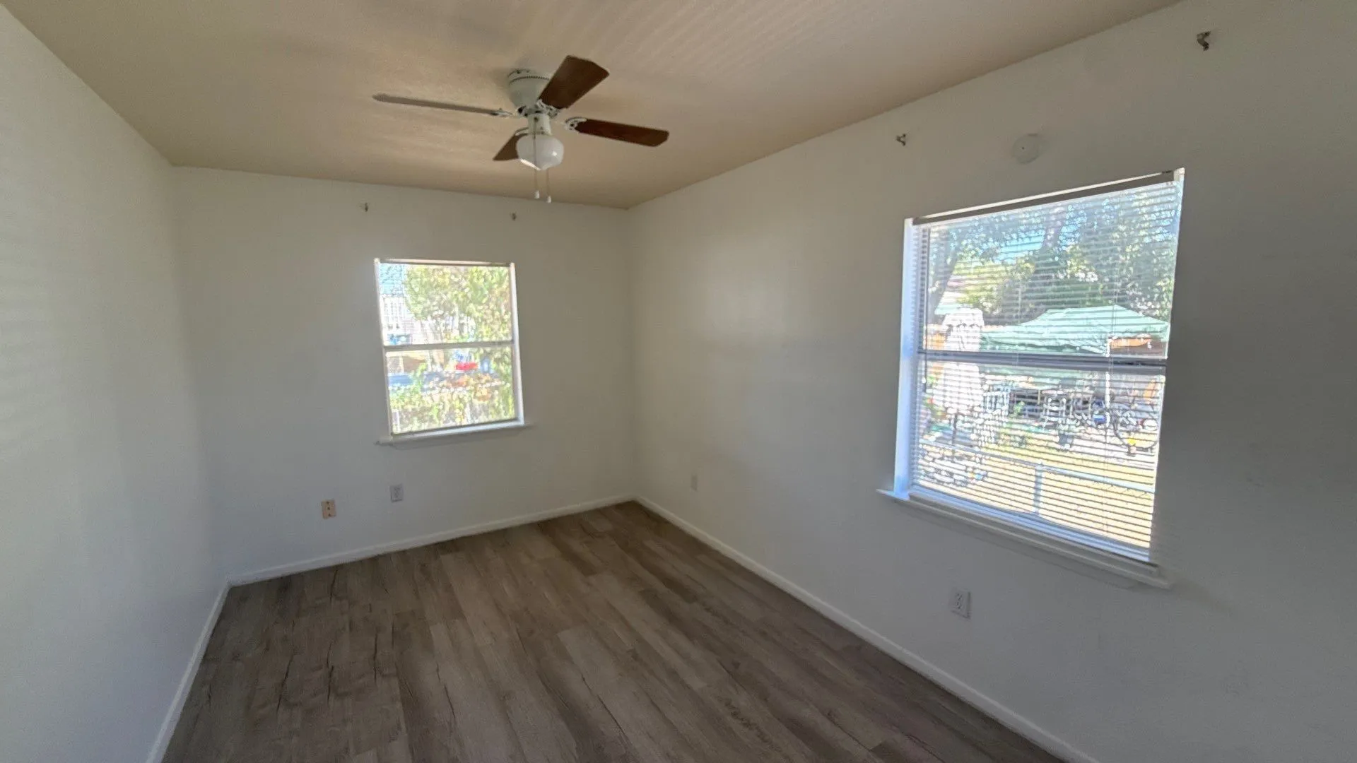 Wood-finish flooring, white walls, and a ceiling fan with light fixture