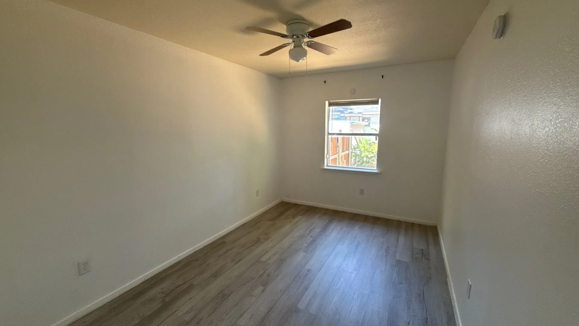 Wood-finish flooring, ceiling fan, and a window providing natural illumination