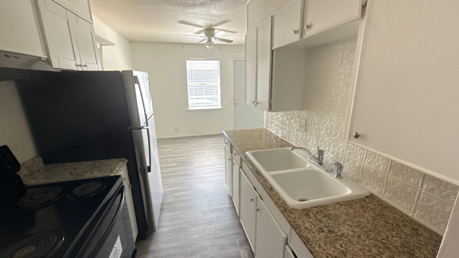 Kitchen with granite-finish countertops, a double basin sink, and white cabinetry