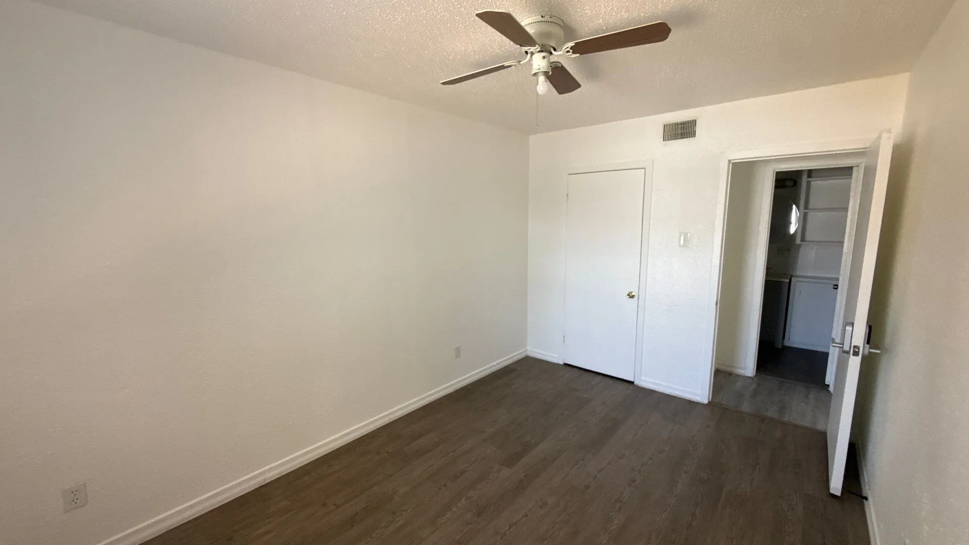 Wood-finish flooring, white walls, and a ceiling fan with light fixture