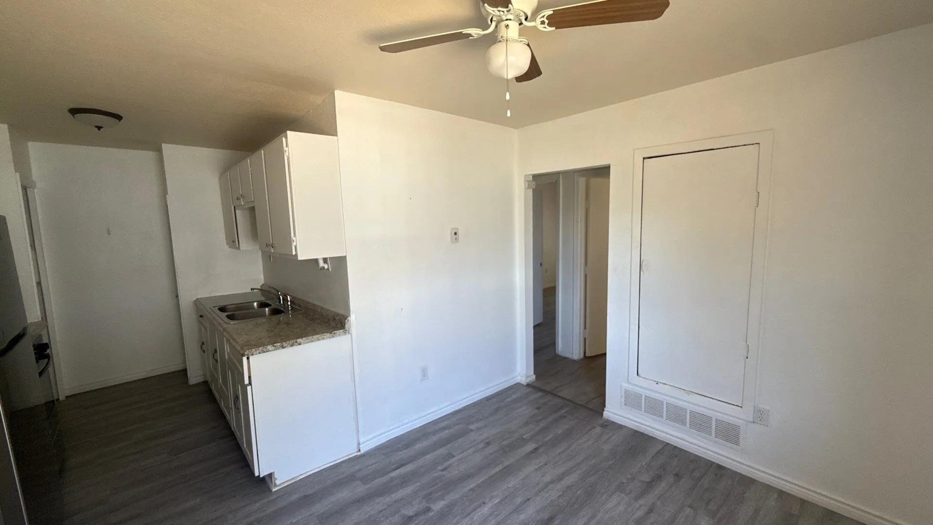 Kitchenette with white cabinetry, granite-style countertops, and a double basin stainless steel sink