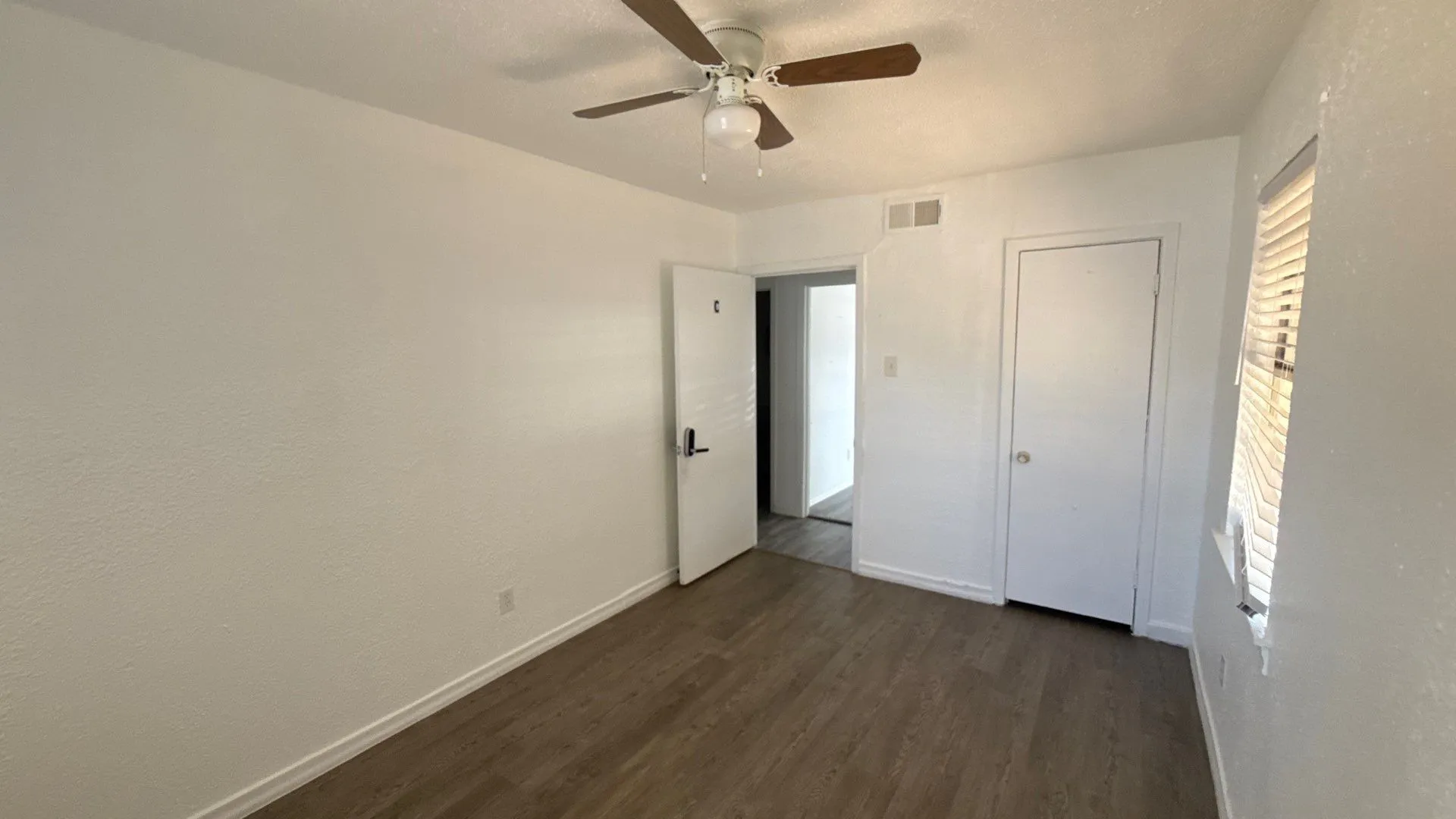 Wood-finish flooring, ceiling fan, white interior paint, and window with blinds