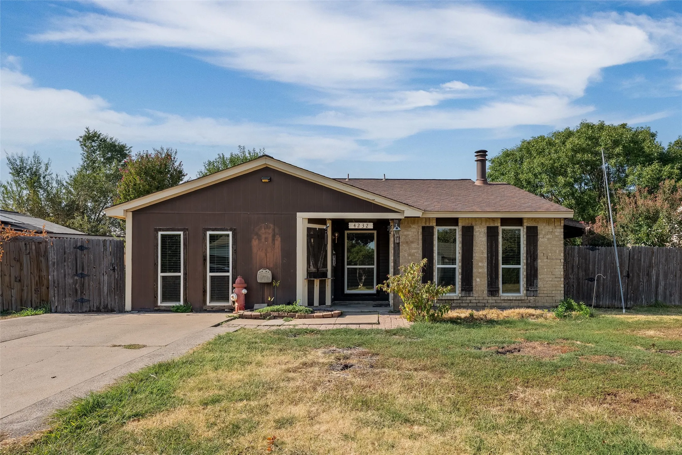 Exterior featuring a combination of brick and siding, a driveway, and a front yard