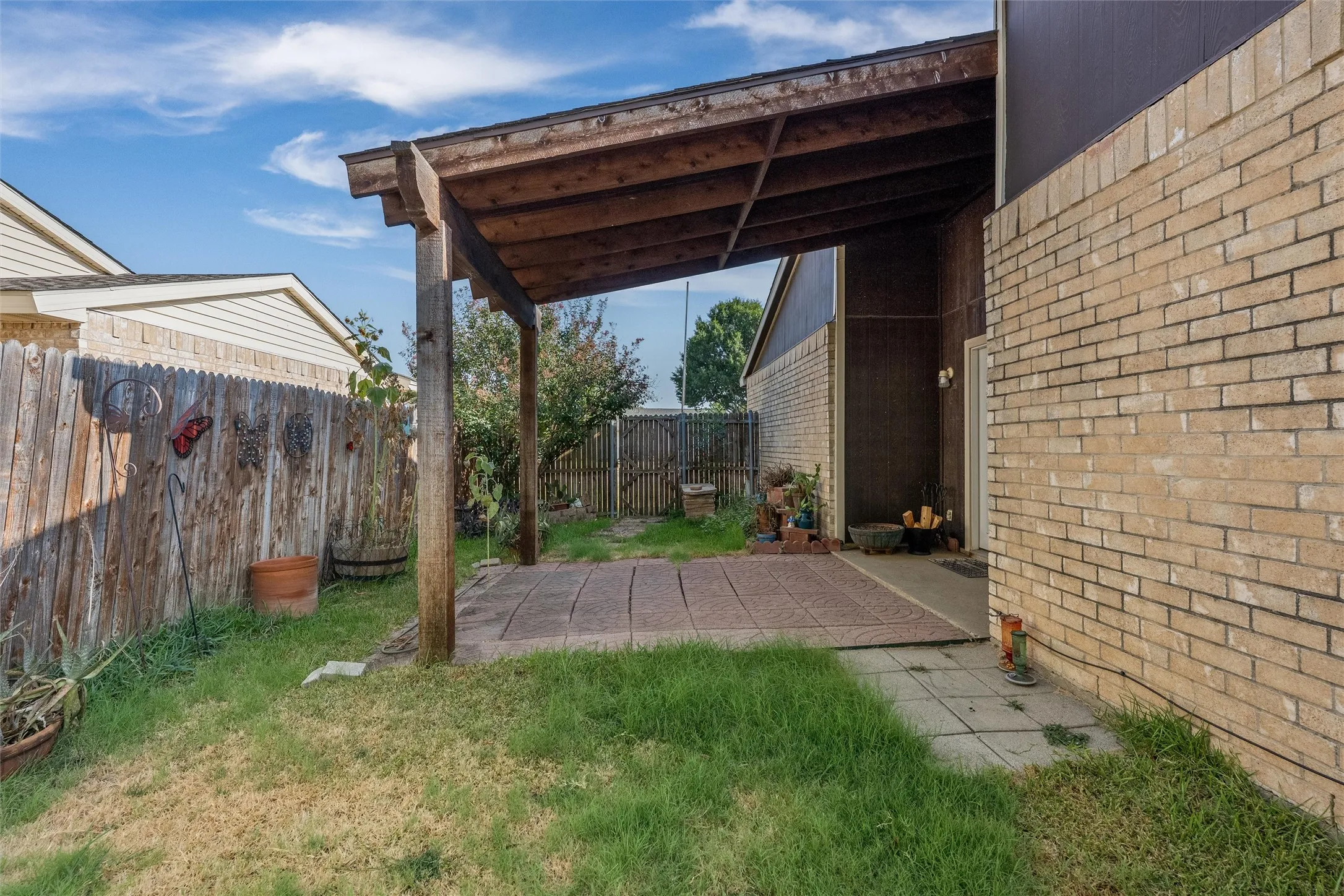 Rear patio featuring an overhead wood pergola, brick exterior, and a fenced yard