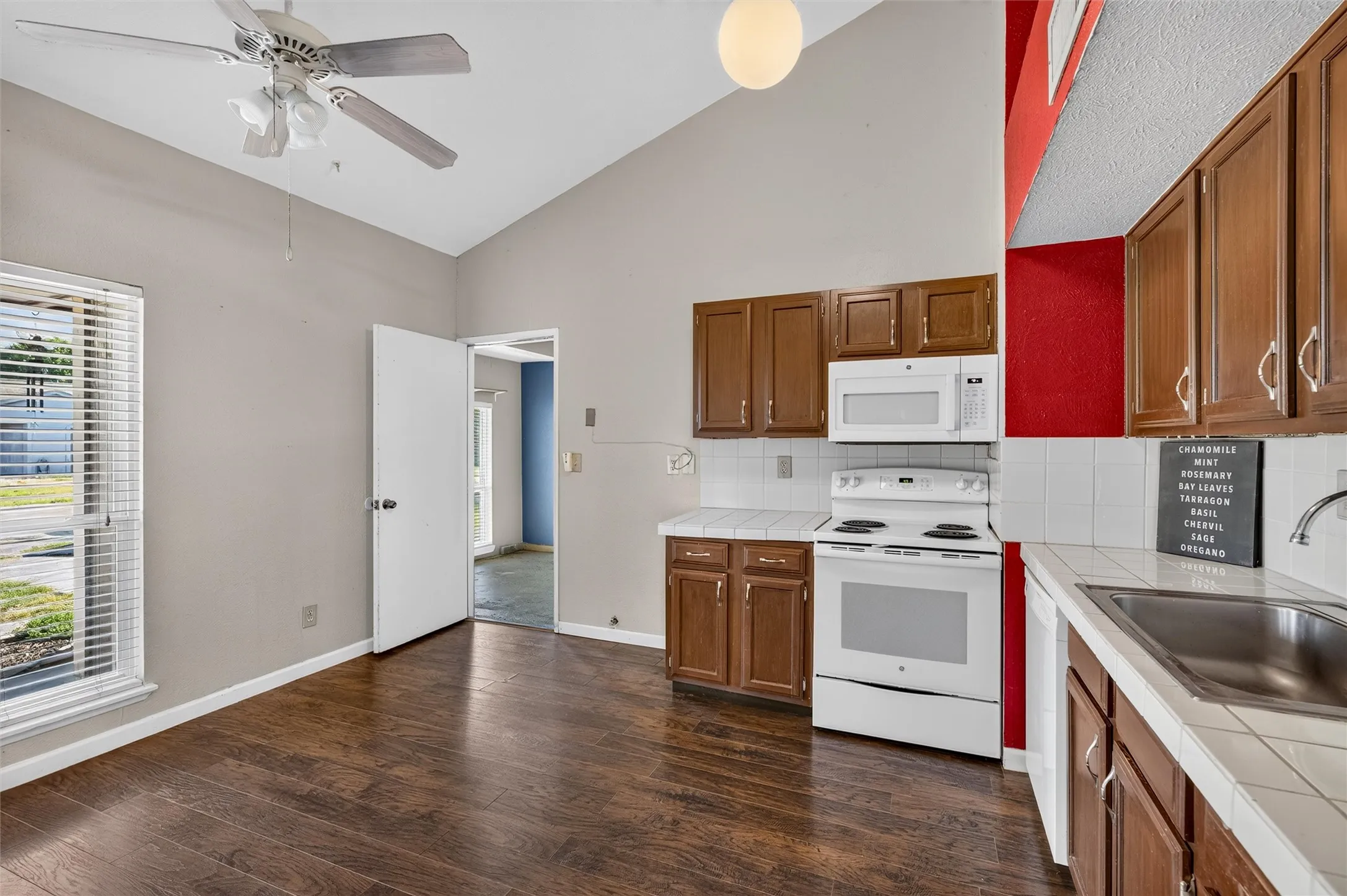 Kitchen featuring wood-finish flooring, vaulted ceiling, and built-in white appliances