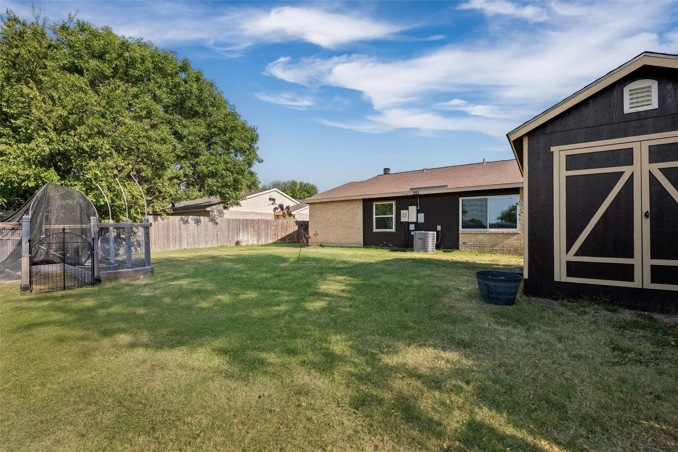 Expansive backyard featuring a manicured lawn, established privacy fencing, and a dedicated storage shed