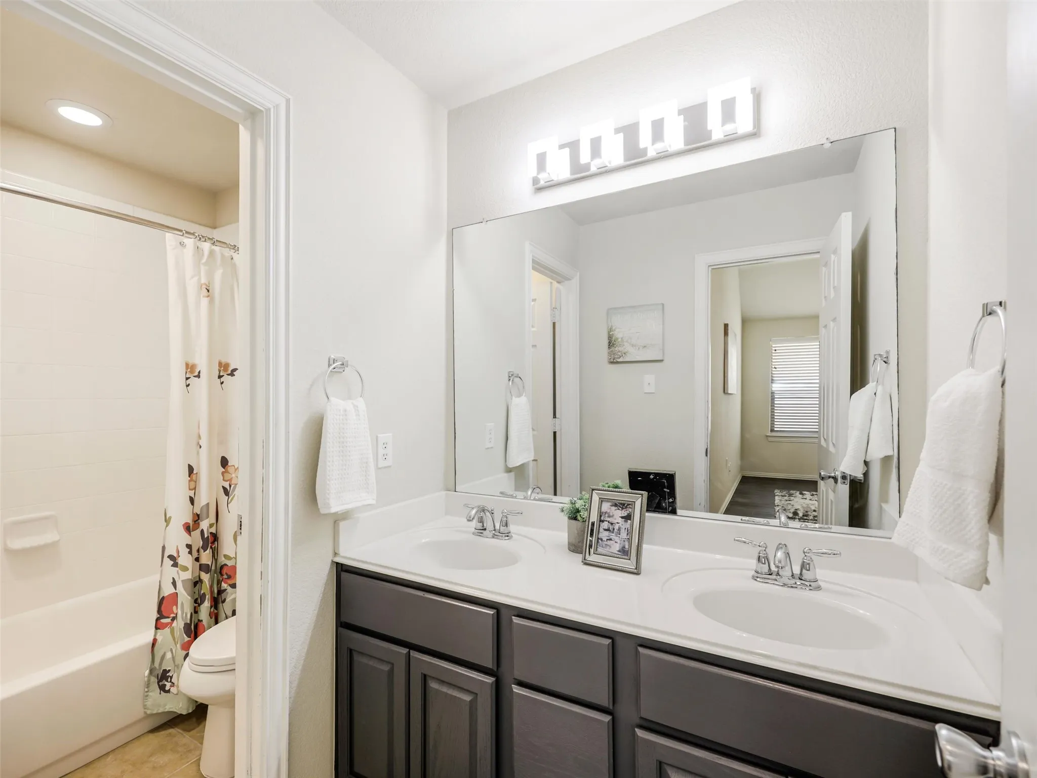 Secondary bathroom includes a dual-sink vanity, oversized mirror, generous counter space, and a separate tub and shower area.