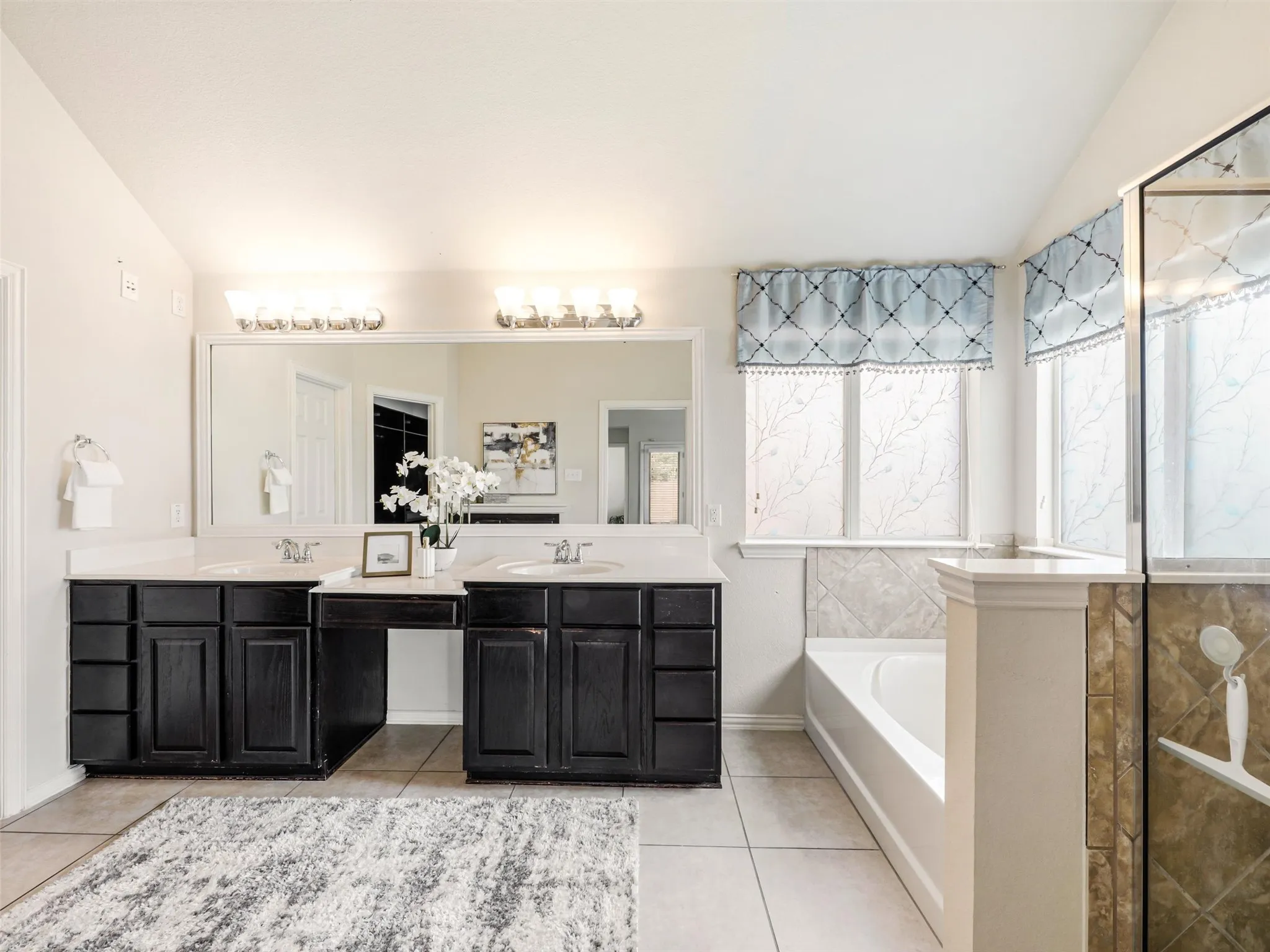 Relax and recharge with a separate soaking tub and tiled walk-in shower, surrounded by multiple windows for natural light.