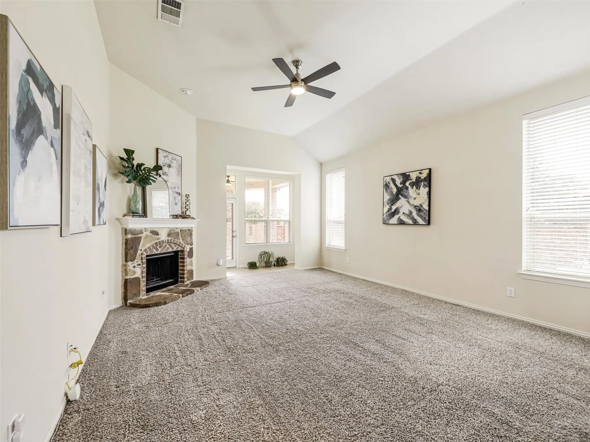 Large windows fill the living room with natural light, while the stone fireplace creates a warm and inviting focal point.